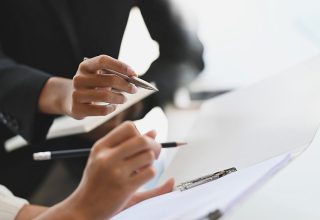 Closeup two woman consulting with paperwork document report.