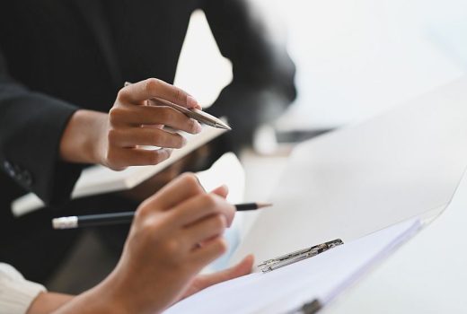Closeup two woman consulting with paperwork document report.